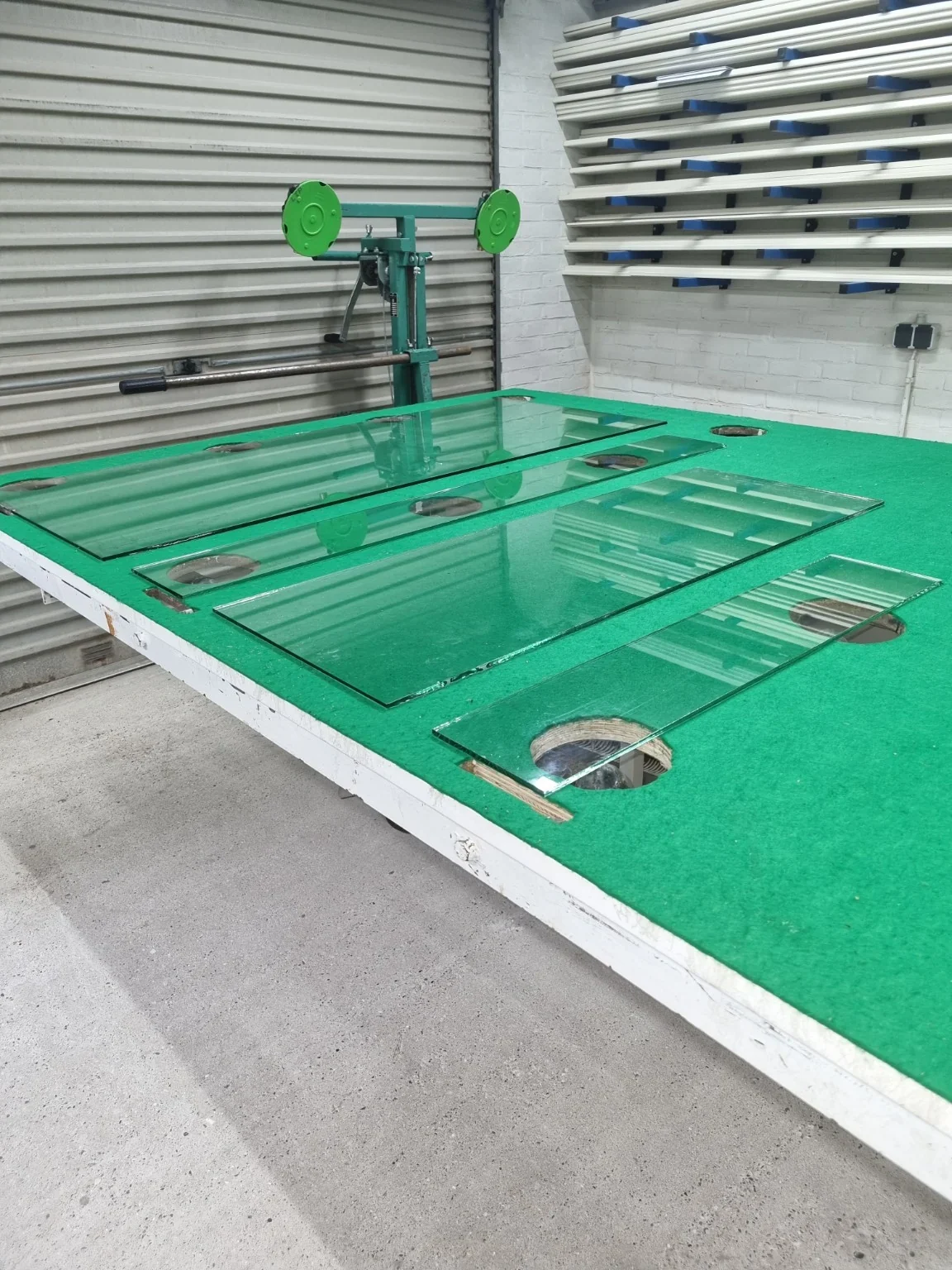 Op maat gesneden ruiten van enkel glas op de groene snijtafel in de eigen werkplaats van Voorne Glasmontage