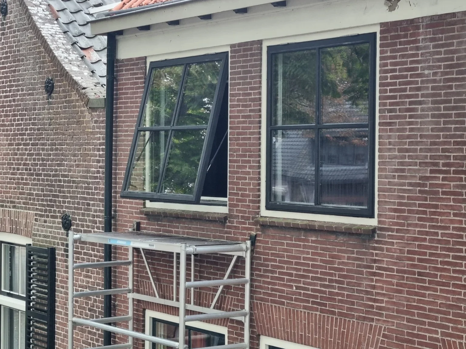 Twee grote donkere klapramen met dubbel glas en Weense roeden in de bestaande witte kozijnen in Burgh-Haamstede